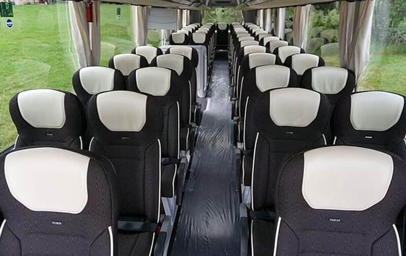 Innenraum eines großen Reisebusses mit verstellbaren Sitzen und Mittelgang